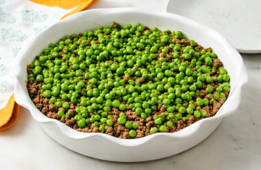 Step-by-step preparation of shepherd’s pie in a white ceramic dish with beef, peas, and mashed potatoes